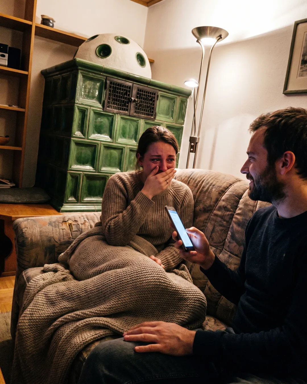 Paar am Sofa, sie hält sich gerührt die Hand vor den Mund