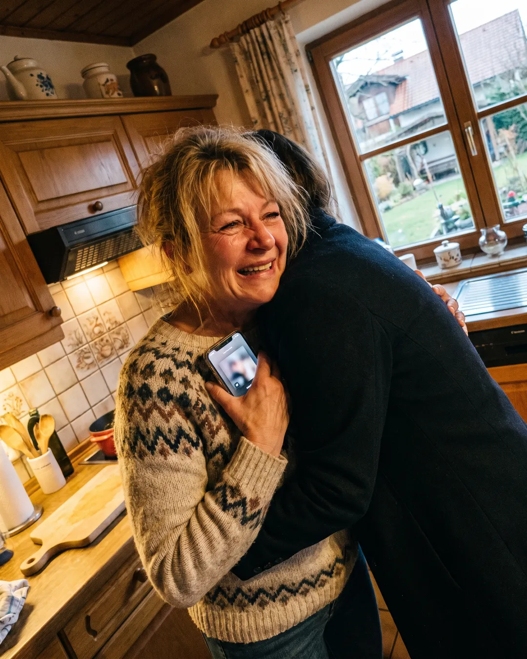 Mama in der Küche, das Handy an die Brust gedrückt