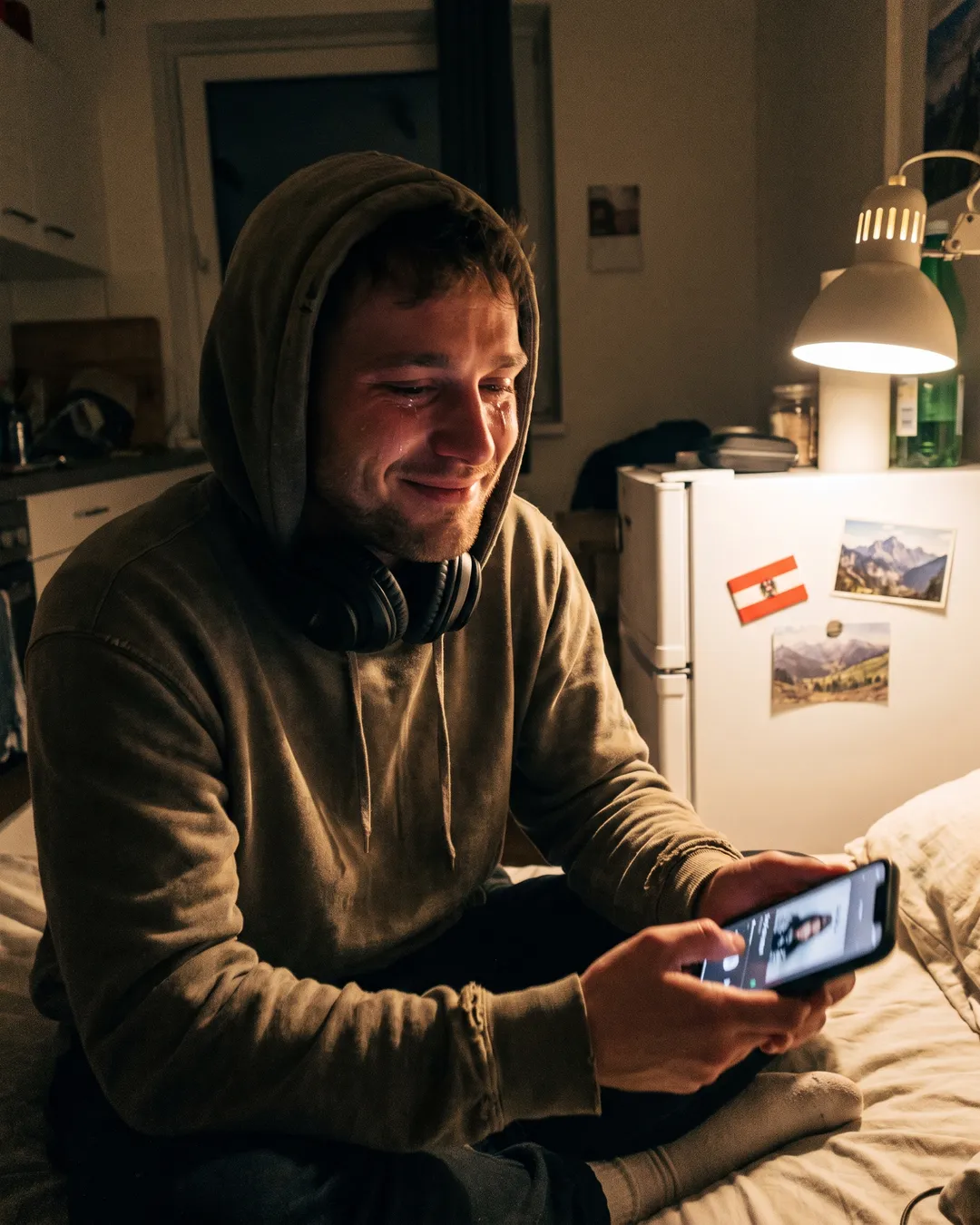 Junger Mann im Ausland am Bettrand, sichtlich bewegt