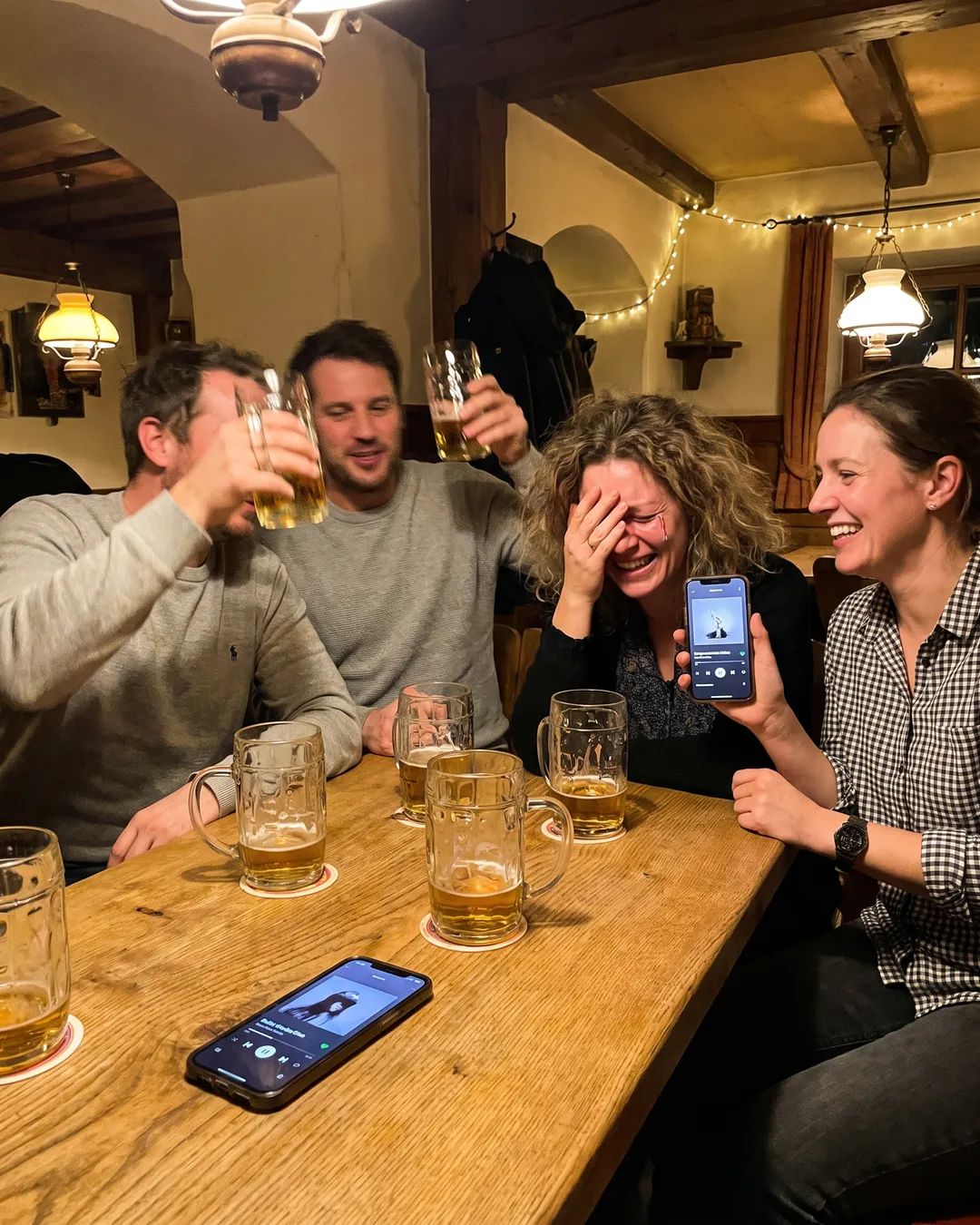 Freundesrunde am Stammtisch, einer hält das Handy hoch